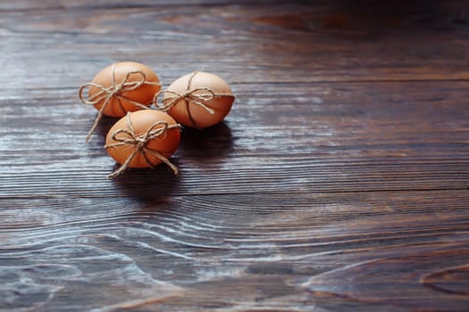 Easter beige eggs decorate with rope on brown wooden background with copyspace