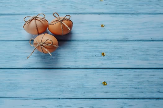 Easter beige eggs decorate with rope on blue wooden background with copyspace