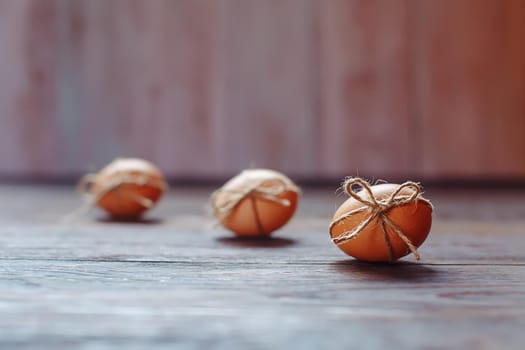 Easter beige eggs decorate with rope on brown wooden background with copyspace