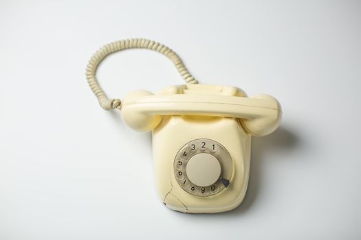 White retro rotary telephone with cracks and broken parts on white background