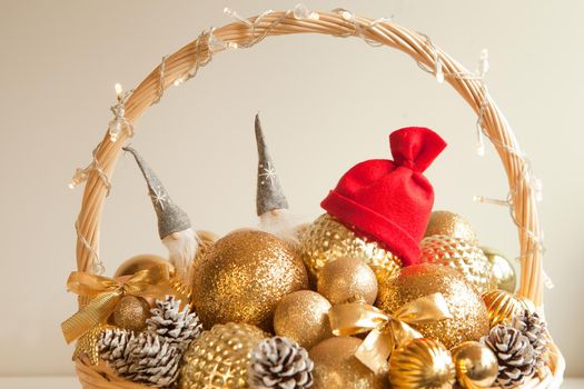 golden balls at huge wicker basket with red santa hat. decoration for Christmas fir tree or apartmen. Christmas preparations. wicker filled to the top with golden balls