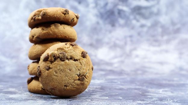 American chocolate chip cookies stacked on top of each other on a beautiful gray marble background. Traditional rounded crunchy dough with chocolate chips. Delicious dessert, pastries. Copy space.