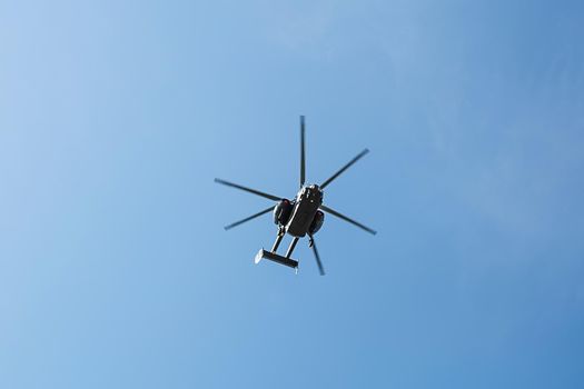 Small civil helicopter flies against a blue sky with clouds background, transportation concept