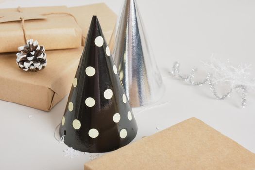 party hats and gifts boxes on gray background, shiny festive new year or christmas decor, christmas gift box and decorations