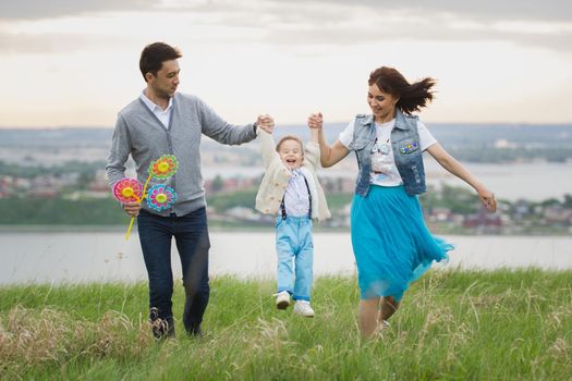 Young couple with a child dancing and having fun in nature, sunset, telephoto shot