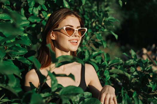 smiling woman wearing sunglasses green leaves nature fashion. High quality photo