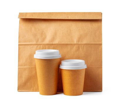 Craft paper bag and coffee to go cups on white background close up