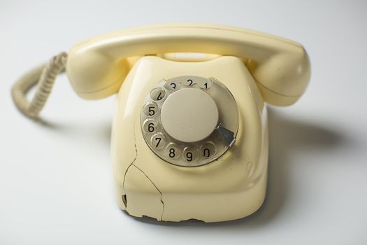 White retro rotary telephone with cracks and broken parts on white background