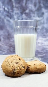 American gluten free chocolate chip cookies with glass glass of vegetable milk on gray background. Chocolate chip cookies. Sweet pastries, dessert. Culinary background. Vertical photography