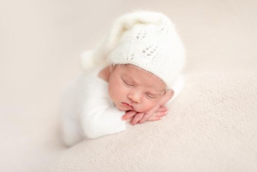 Innocent newborn angel in white knitted suit