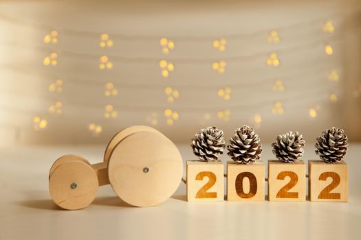 wooden car driving new year numbers 2022 and pine cones. toy car carrying wooden blocks. new year celebration and approach. Happy New year. Copy space.