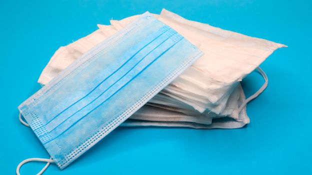 Coronavirus protection. Antiviral protective medical face masks with ear loops. Surgical mask background. Respiratory syndrome, coronavirus disease COVID-19. Many folded medical masks