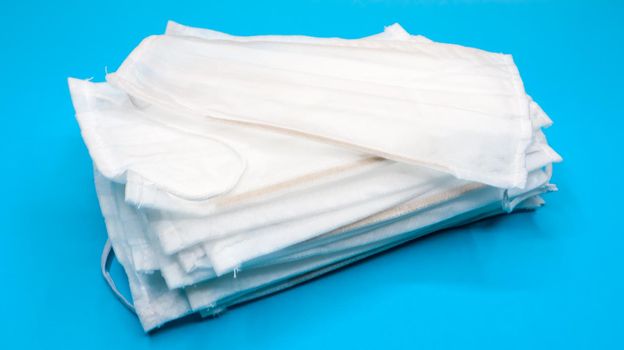 Coronavirus protection. Antiviral protective medical face masks with ear loops. Surgical mask background. Respiratory syndrome, coronavirus disease COVID-19. Many folded medical masks