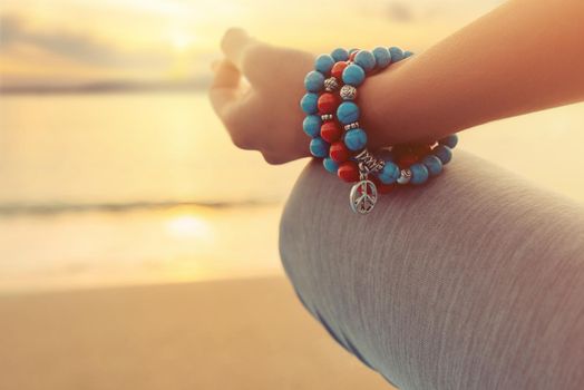 Close-up view of hand of woman meditating in pose of lotus on beach in front of sea.