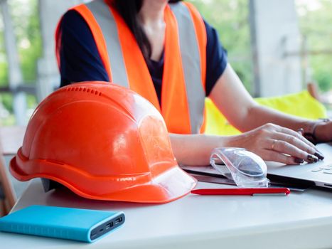 Close-up of a construction safety helmet lies. Woman builder working on a construction site on behind a laptop