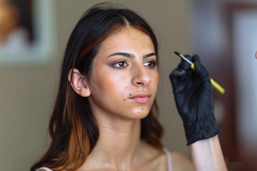 Beautiful model in make up process. Portrait of young pretty woman with beutiful makeup in beauty studio salon. Evening make up, blurry background