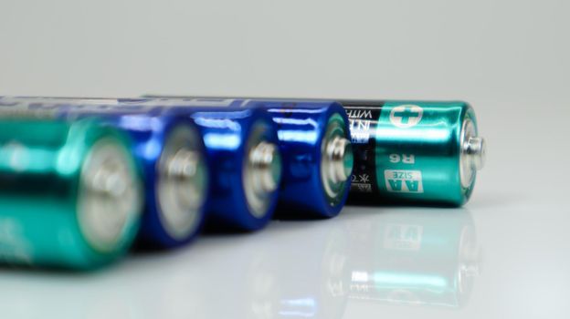 AA alkaline rechargeable batteries on white glossy background with reflection with copy space