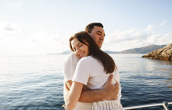 Young loving couple hugging standing on the yacht in the sea, close up