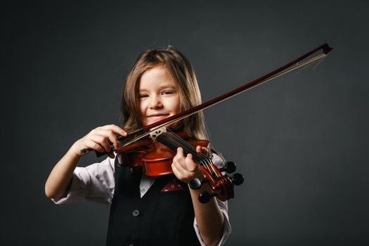Beautiful smiling girl with long hair playing violin