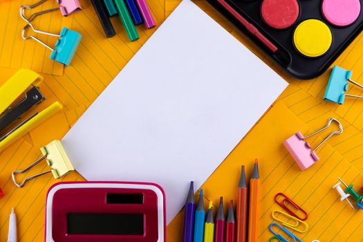 School office supplies stationery on a orange paper background with copy space. Back to school concept.