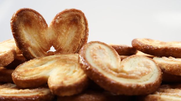 Fresh puff pastry palm cookies in the shape of a heart. Classic French pastries. Pig ear, elephant ear cookies, French hearts