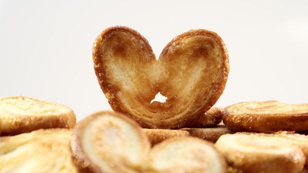 Fresh puff pastry palm cookies in the shape of a heart. Classic French pastries. Pig ear, elephant ear cookies, French hearts