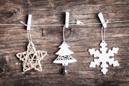White christmas decorations attached to the rope, over wooden background