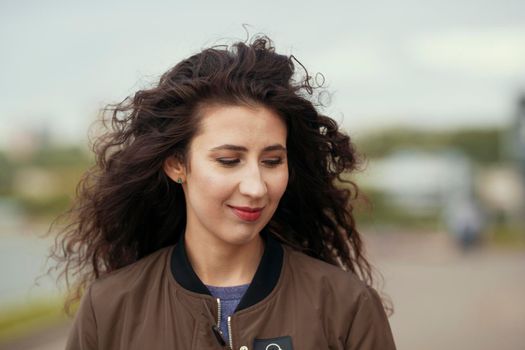 Portrait of attractive young brunette woman with long curly hair, close up