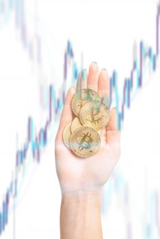 Symbol of crypto currency - bitcoin on female palm hand on background of growth infographic.