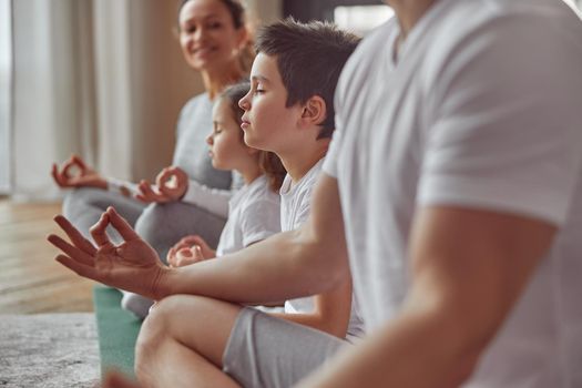 Cropped head of smiling woman watching her husband and kids doing mental practice at home together