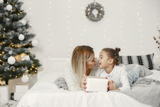 People reparing for Christmas. Mother playing with her daughter. Family is resting in a festive room. Child in a sweater sweater.