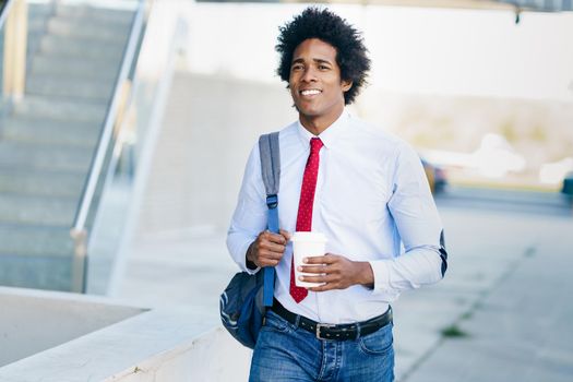 Black Businessman walking down the street with a take-away glass. Man with afro hair.