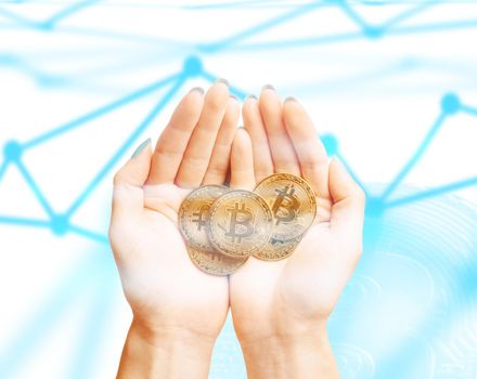 Many gold coins bitcoins in female hands on background of blockchain scheme, top view.