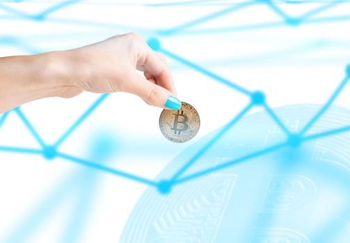 Woman’s hand holding gold coin bitcoin on background of blockchain concept.