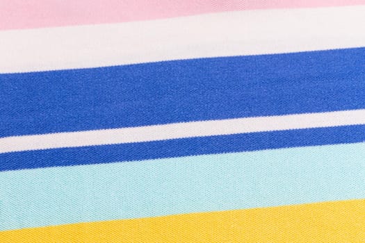 Beautiful summer background made of striped fabric of delicate colors blue, yellow, pink.