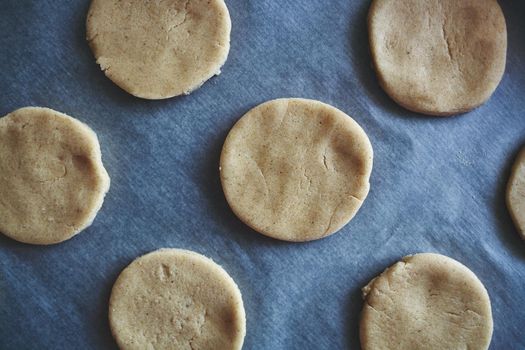 Round pieces of shortbread dough for making cookies or gingerbread are on paper. Homemade baking with your own hands. Top view