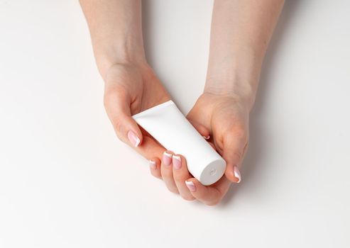 Female hand holding cosmetic bottle on white background