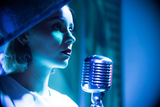 Young attractive woman standing on the stage near the mic. Portrait