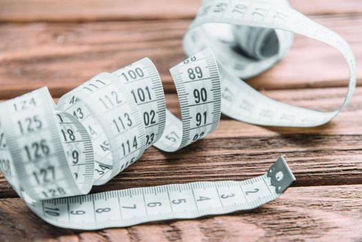 Measuring tape for tailoring on a wooden table, close-up.