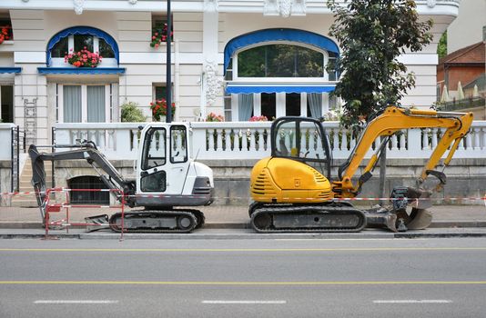 Small white and yellow excavator on the road in France Smooth road