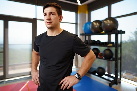 Portrait of a young handsome fitness trainer in a gym, close up