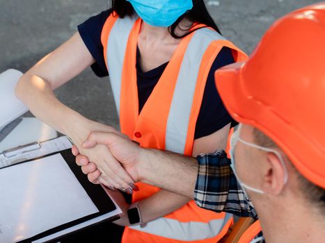 Woman and man builders in helmets signed a contract outside the office space in the open air