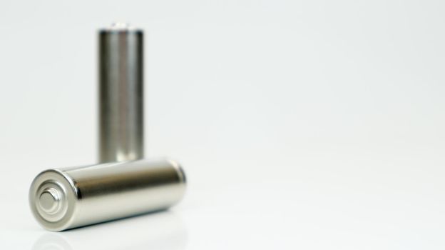 AA alkaline rechargeable batteries on white glossy background with reflection. Close up two empty batteries with copy space