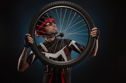 a guy-cyclist in a Bicycle helmet with a Bicycle wheel