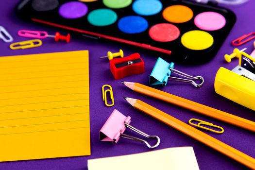 School office supplies stationery on a purple background desk with copy space. Back to school concept.