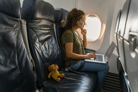 Busy woman working with laptop while sitting on the seat on the plane during the flight. Work concept