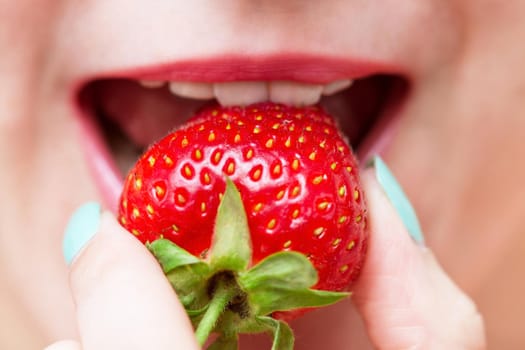 Close up of a female mouth eating a fresh strawberry