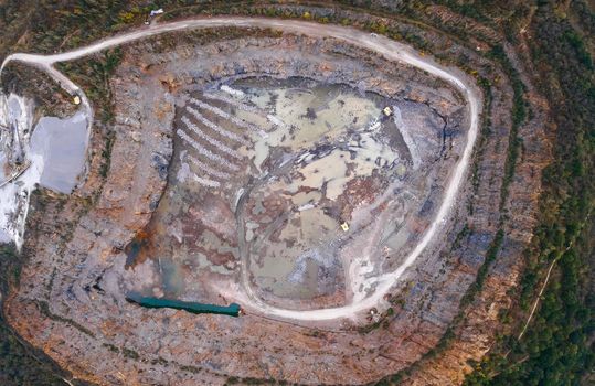Aerial drone view of career in Europe at summer sunset, crushed stone quarry, beautiful nature round, some excavators, diggers inside