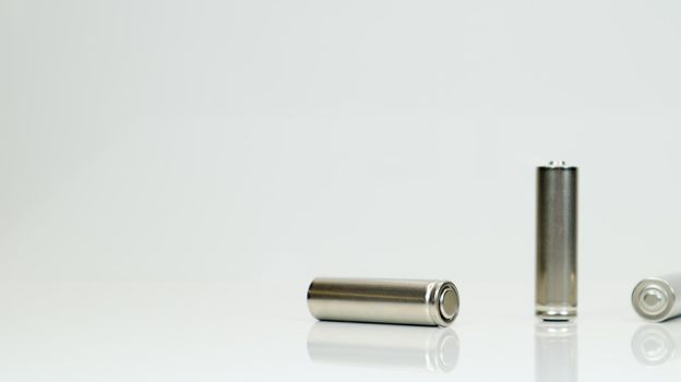 AA alkaline rechargeable batteries on white glossy background with reflection. Close up three empty batteries with copy space