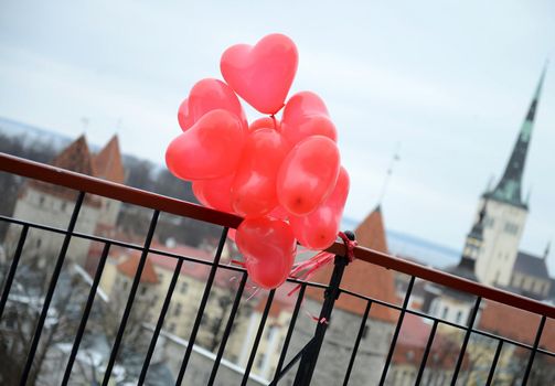 Red Hearts Balloons behind the panoramic view of European Tallinn Old City for Valentine Day love story in Estonia. Travel concept. Surprising